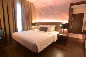 加拉旺美居加拉璜酒店的卧室配有一张白色大床,墙上挂有绘画作品