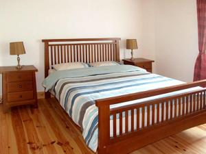 Kilkieran1 Clancy Cottages的一间卧室配有一张床、两个床头柜和两盏灯。