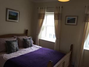Cross Hands94 High Street的一间卧室配有一张带紫色床单的床和窗户。