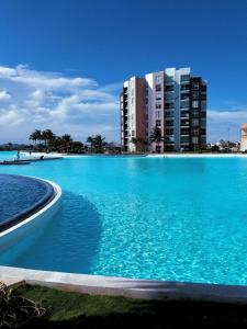 坎昆Departamento en Dream Lagoons Cancun的一座蓝色的游泳池,位于一些建筑前面