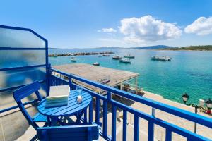 艾丽奇Angeliki Seaside Hotel的蓝色椅子,坐在阳台,俯瞰着水体