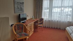 魏勒-锡默贝格帕斯特酒店的客房设有一张桌子、一台电视和两把椅子