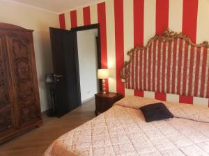 萨尔扎纳B&B Al Calcandola的一间卧室配有一张床和红色及白色条纹墙