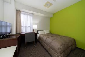 广岛广岛和平公园经济型酒店的一间卧室配有一张床、一张书桌和一台电视