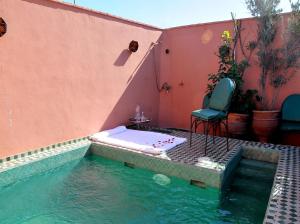 马拉喀什里亚德莉拉庭院旅馆的房屋旁的游泳池配有桌子和椅子