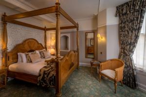 巴克斯顿老霍酒店的一间卧室配有一张天蓬床和一把椅子