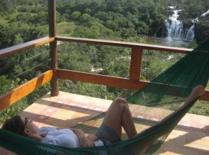 戈亚斯州上帕莱索Pousada Cachoeira Poço Encantado的躺在瀑布前的吊床上的女人