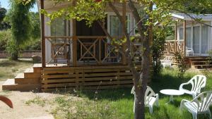 卡尔维Camping Les Castors的一座房子,里面摆放着白色的椅子和桌子,还有一棵树