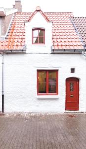 根特Romantic 16th century workers house的白色的房子,有红色的窗户和红色的门