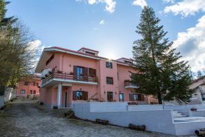 塞拉圣布鲁诺Il Moscardino Country Resort的前面有棵树的粉红色建筑