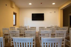塞拉圣布鲁诺Il Moscardino Country Resort的一间设有白色椅子和平面电视的房间