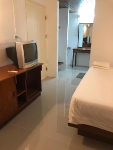 春蓬帕拉多恩旅馆的一间卧室配有一张床和一张书桌上的电视