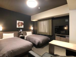 土浦市Hotel Route-Inn Tsuchiura的酒店客房设有两张床和一台平面电视。