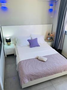 巴特亚姆Motel Hofim的卧室配有白色床和紫色枕头