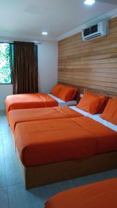 瓜拉大汉Naura Roomstay的配有橙色床单的酒店客房内的两张床