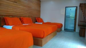 瓜拉大汉Naura Roomstay的带3张床、橙色床单和窗户的客房