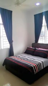 阿罗士打Home2u Alor Setar Homestay的一张位于带蓝色窗帘和窗户的房间的床铺