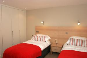 PerranwellThe Valley的卧室设有两张红色和白色的床