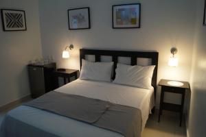 圣多明各加勒比城市精品酒店的一间卧室配有一张带两张桌子和两盏灯的床。