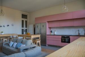波尔图Sweet Swell的带沙发的客厅和带粉红色橱柜的厨房。