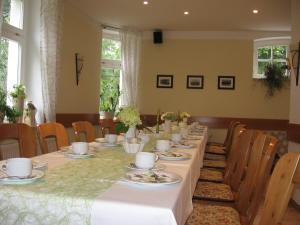 措伊伦罗达Pension Kastanienhof的一间用餐室,配有带盘子和杯子的长桌