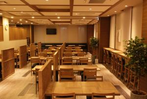 IshiokaHotel Route-Inn Ishioka的一间设有木桌和椅子的餐厅