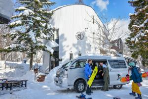 白马村Penke Panke Lodge and Apartments的一群人站在雪地里的一辆面包车后面