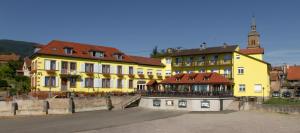 Heiligenstein科勒维内驿站酒店的镇里一座黄色建筑,有钟楼
