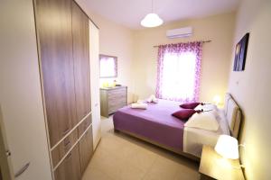科孚镇Luna Bianca - Corfu Apartments的一间卧室设有紫色的床和窗户