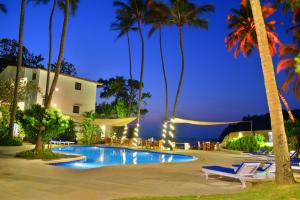 帕纳吉O Pescador an Indy Resort的夜间带游泳池和棕榈树的度假村