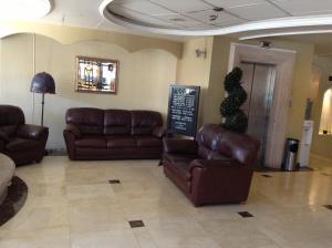 乌鲁阿潘Hotel Real de Uruapan的一间设有棕色皮革沙发和标志的等候室