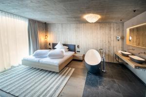 朗根费尔德Glanz & Glory Längenfeld的一间卧室配有一张床、一个浴缸和一个水槽