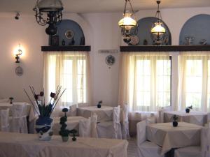 斯科拉Anamar Patmos的一间设有白色桌椅和窗户的用餐室