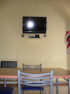 科隆HUGO 3的一张桌子、两把椅子和墙上的电视