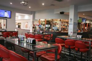 布里斯班Acacia Ridge Hotel & Motel Brisbane的一间设有红色桌椅的餐厅和一间酒吧