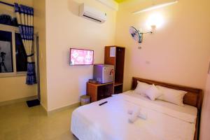 惹岛KHÁCH SẠN GIA THỊNH LÝ SƠN的一间卧室配有一张带白色床单的床和一台电视。