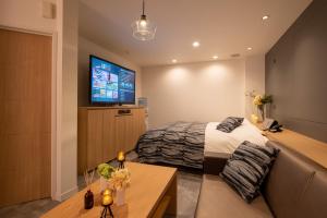 涩川市Hotel Waraku Shibukawa的一间卧室配有一张床和一台平面电视