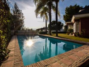 马拉加Villa Antumalal B&B的一座棕榈树游泳池和一座房子