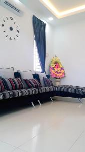 阿罗士打Home2u Alor Setar Homestay的客厅配有一张沙发,墙上挂着一个钟