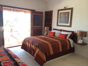 巴卡拉尔Hotel Maria Maria的一间卧室配有一张带红色枕头的床和一扇窗户
