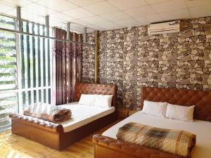 河江Long Hotel and motobike rental的一间卧室配有两张床和真皮沙发