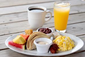 西湾West Bay Colonial的一盘早餐食品和一杯橙汁