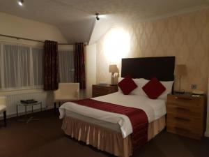 道格拉斯阿斯科特酒店的酒店客房配有一张带红色枕头的大床