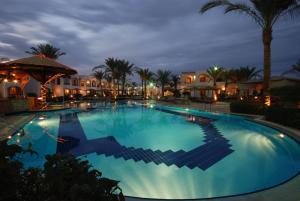 沙姆沙伊赫沙姆沙伊赫珊瑚山庄度假酒店的棕榈树和建筑的夜间游泳池