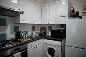 布里斯托Central Located One Bedroom Apt的厨房配有白色橱柜、洗衣机和烘干机