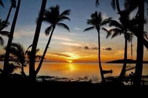 Tavewa椰子海滩度假村的日落时坐在海滩吊床上的人