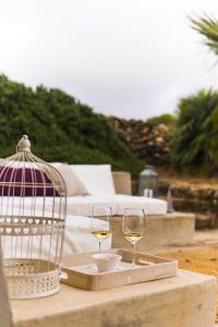 潘泰莱里亚圣安娜达穆索度假屋的一张桌子,上面放着两杯白葡萄酒和一只鸟笼