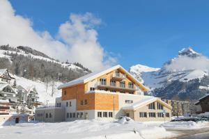 英格堡Hotel Espen的一座雪地中的建筑,背景是一座山