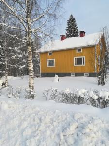 耶姆赛Koskentien kotimajoitus的雪中的一个黄色房子,有院子