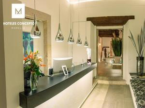 莫雷利亚M Hoteles Concepto的房间里的酒店前台柜台有鲜花